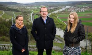 Stefanie Hölscher-Marx (l.), Yvonne Kiesel und Pfarrer Tilman Schneider stehen am Mittwoch (03.04.24) über dem Maintal am terroir f bei Karlstadt.