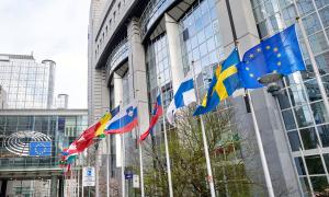 Die Fahnen der EU, Schwedens, Finnlands und mehr vor einem Gebäude aus Glas und Beton