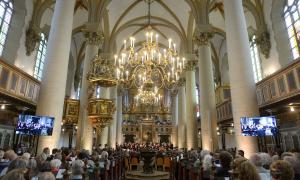 Eine große Kirche, gefüllt mit Menschen, an der Decke ein großer Kronleuchter