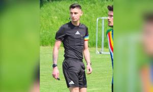 Ein junger Mann im Schiedsrichter-Dress mit einer Regenbogen-Armbinde