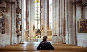 Von hinten abgebildeter Mann sitzt in einer Kirche