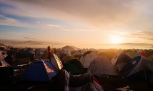 Mehrere Zelte, im Hintergrund geht die Sonne auf oder unter
