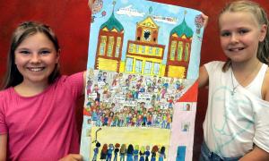Zwei Mädchen halten ein Bild, auf dem Kinder mit Plakaten zu sehen sind