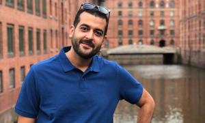 Ein Mann im blauen Polohemd, hinter ihm Backsteinwände