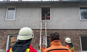 Feuerwehrleute an einer Leiter vor einem Haus