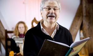 Der Autor Paul Maar hält ein Buch in der Haus, aus dem er vorliest
