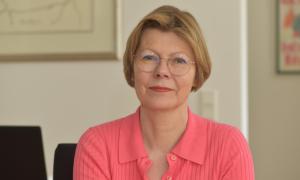 ältere Frau mit Brille und blondem Bob schaut in die Kamera