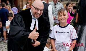 Ein Mann im Talar und ein Junge im T-Shirt