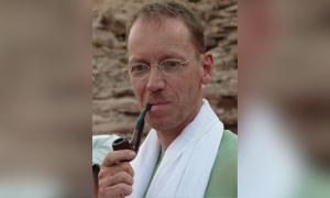 Ein Mann mit Brille, eine Pfeife im Mund