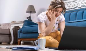 Eine Frau schaut verzweifelt auf ein Laptop