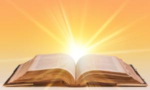 Hinter einer aufgeschlagenen Bibel geht die Sonne auf