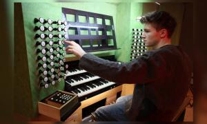 Ein junger Mann sitzt an einer Orgel