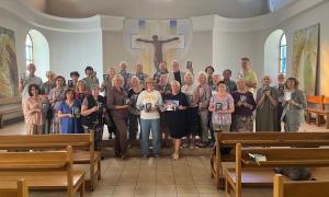 Viele Menschen stehen in einer Kirche und halten Gesangbücher