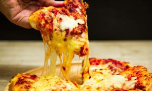Eine Pizza, der Käse zieht Fäden, eine Hand hält ein Stück davon