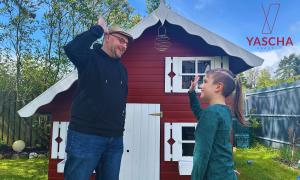 Ein Junge und ein Mann vor einer Gartenhütte, sie geben sich High Five