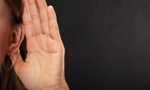 Eine Frau hält ihre Hand ans Ohr