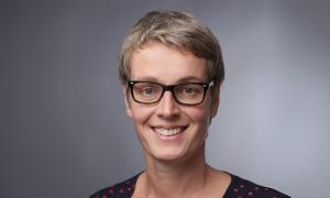 Eine Frau mit kurzen Haaren und Brille lächelt