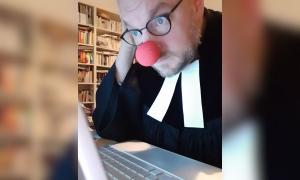 Ein Mann mit roter Clownsnase und Pfarrer-Gewand