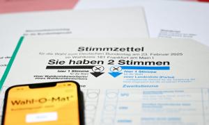 Ein Stimmzettel zur Bundestagswahl mit der Aufschrift "Sie haben 2 Stimmen". Darüber liegt ein Smartphone mit der Applikation "Wahl-O-Mat" geöffnet.