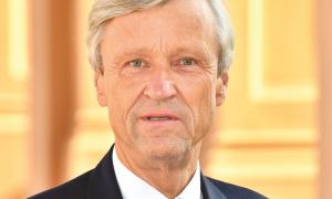 Ein Mann mit grauen Haaren und Anzug blickt in die Kamera