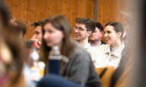 Junge Menschen sitzen in Reihen zusammen