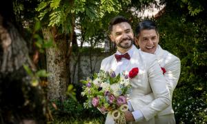 Zwei Männer in weißen Anzügen mit einem Blumenstrauß