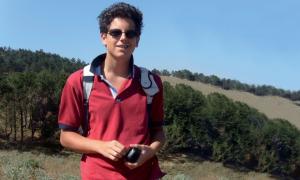 Ein Junge im roten Poloshirt vor bergigem Hintergrund