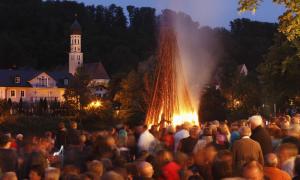 Ein Feuer, abends, im Hintergrund eine Kirche, drumherum Menschen