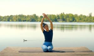 Eine Frau in einer Yogapose auf einem Steg am See