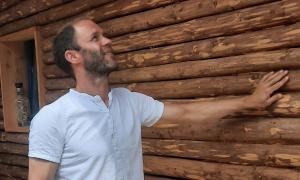 Ein Mann legt seine Hand auf eine Holzwand und schaut nach oben
