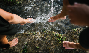 Zwei Menschen tauchen ihre Füße ins Wasser eines Baches