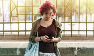 Frau mit roten Haaren am Smartphone unterwegs