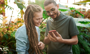 Zwei Menschen schauen in ein Handy und lachen. 