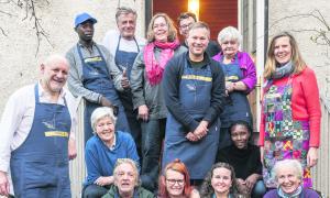 Menschen stehen und sitzen in zwei Reihen vor einer Tür
