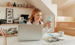 Frau sitzt mit Handy am Rechner