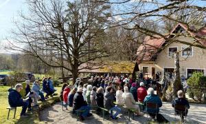 Menschen sitzen vor einem Haus auf Stühlen