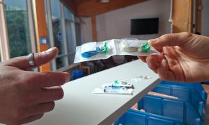 Eine Hand reicht in Plastik verpackte Sachen an eine andere Hand
